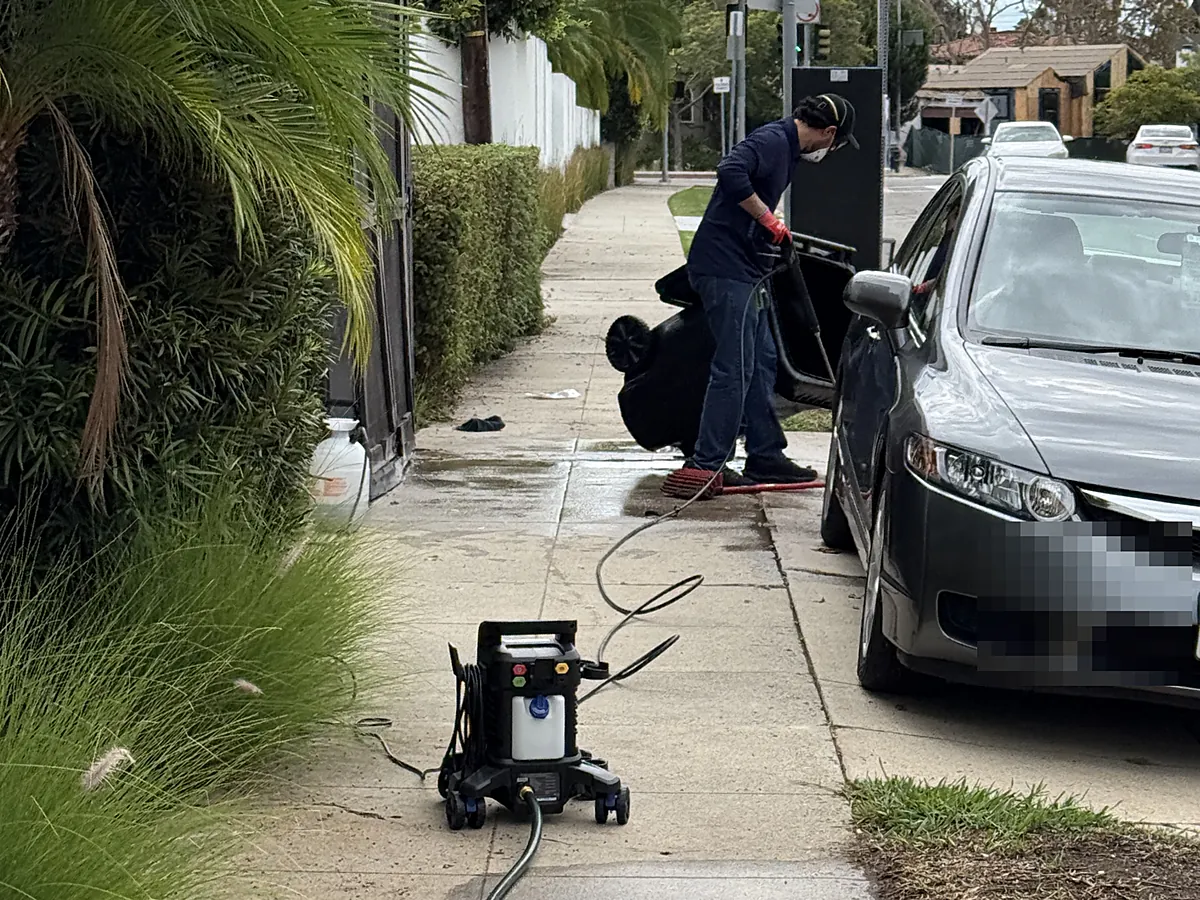 BrightBin pressure washing a trash bin at the curb in Los Angeles